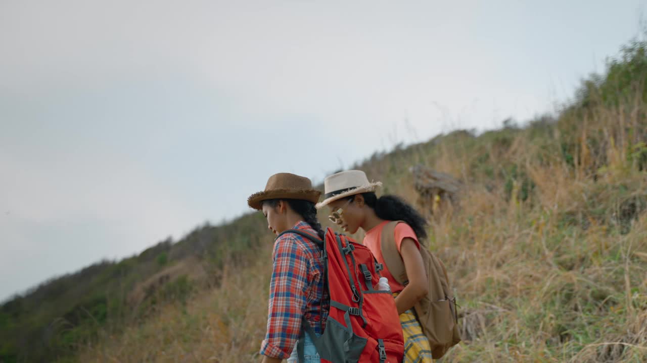 爱冒险的女孩在陡峭的山坡上徒步旅行;成功、冒险、团队合作、放松、自然的概念。视频素材