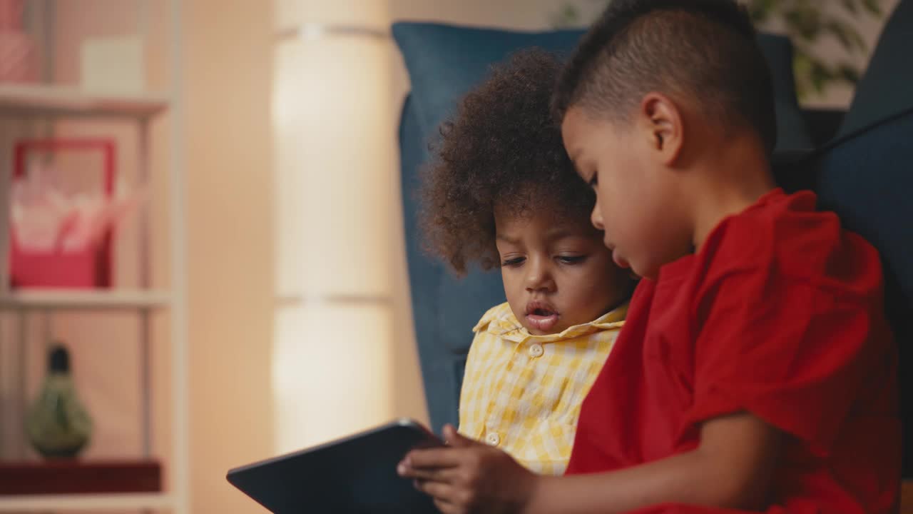 一个非裔美国男孩和他的兄弟在平板电脑上玩游戏，开发应用程序视频下载