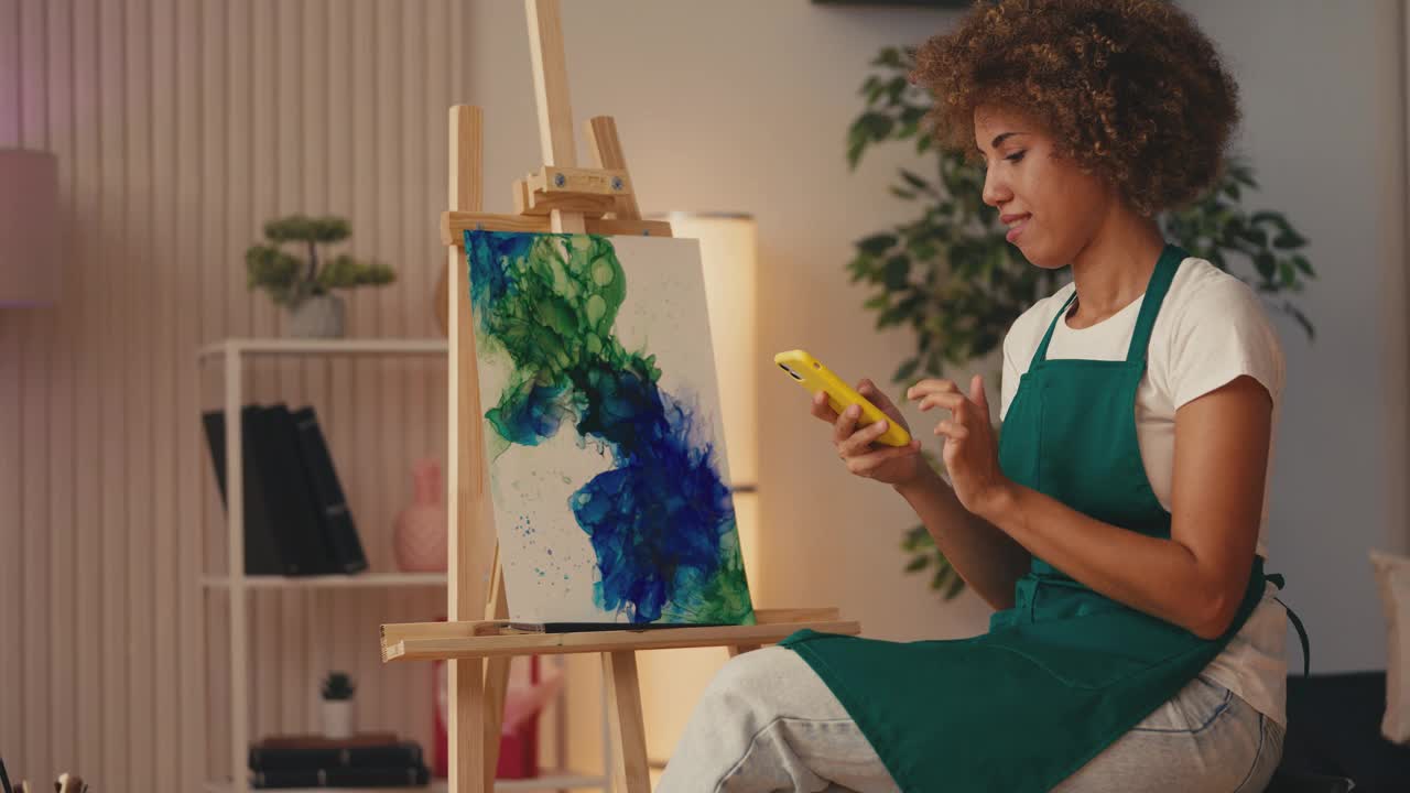 快乐的非裔美国女艺术家用手机在网上出售她的照片视频下载