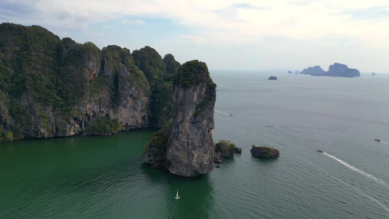 一个幽静的海湾，绿松石般的水，周围是高耸的悬崖，覆盖着郁郁葱葱的绿色植被。魔术航拍飞行全景轨道无人机视频素材