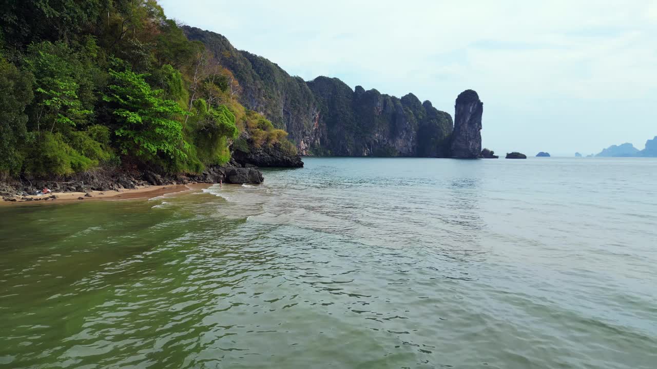 一个幽静的海湾，绿松石般的水，周围是高耸的悬崖，覆盖着郁郁葱葱的绿色植被。不错的鸟瞰图无人机视频素材