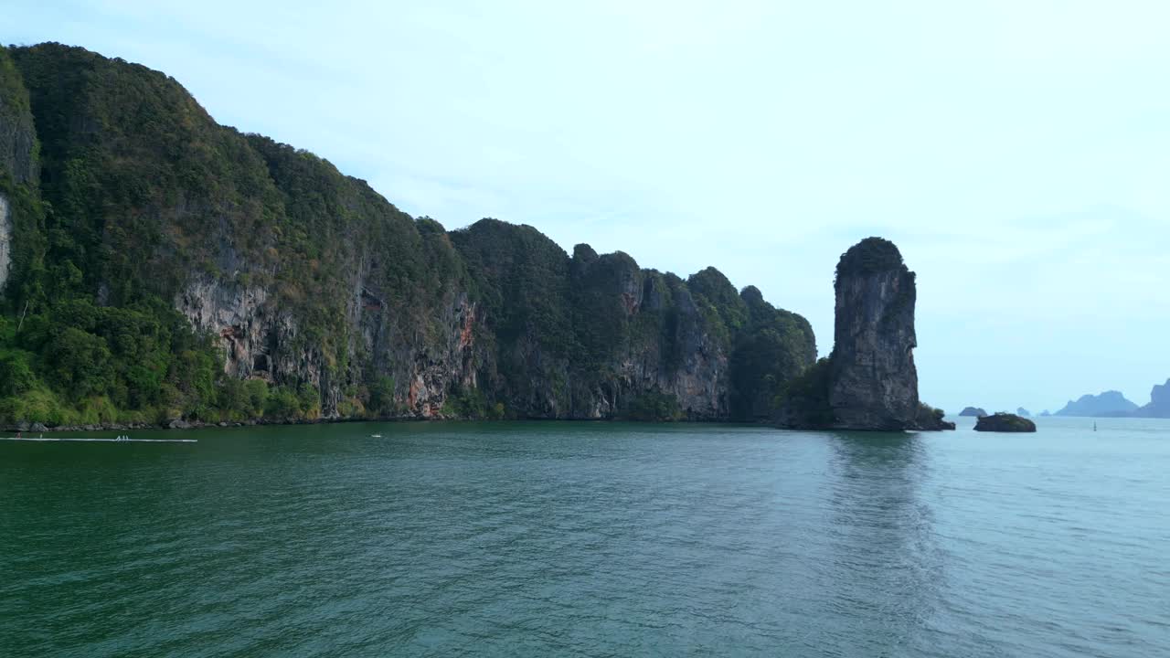 一个幽静的海湾，绿松石般的水，周围是高耸的悬崖，覆盖着郁郁葱葱的绿色植被。令人惊叹的鸟瞰图飞行上升无人机视频素材