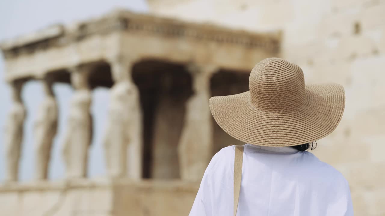 一位戴着帽子的时尚女游客在希腊雅典卫城埃瑞希提翁的女像柱门廊上观光视频素材