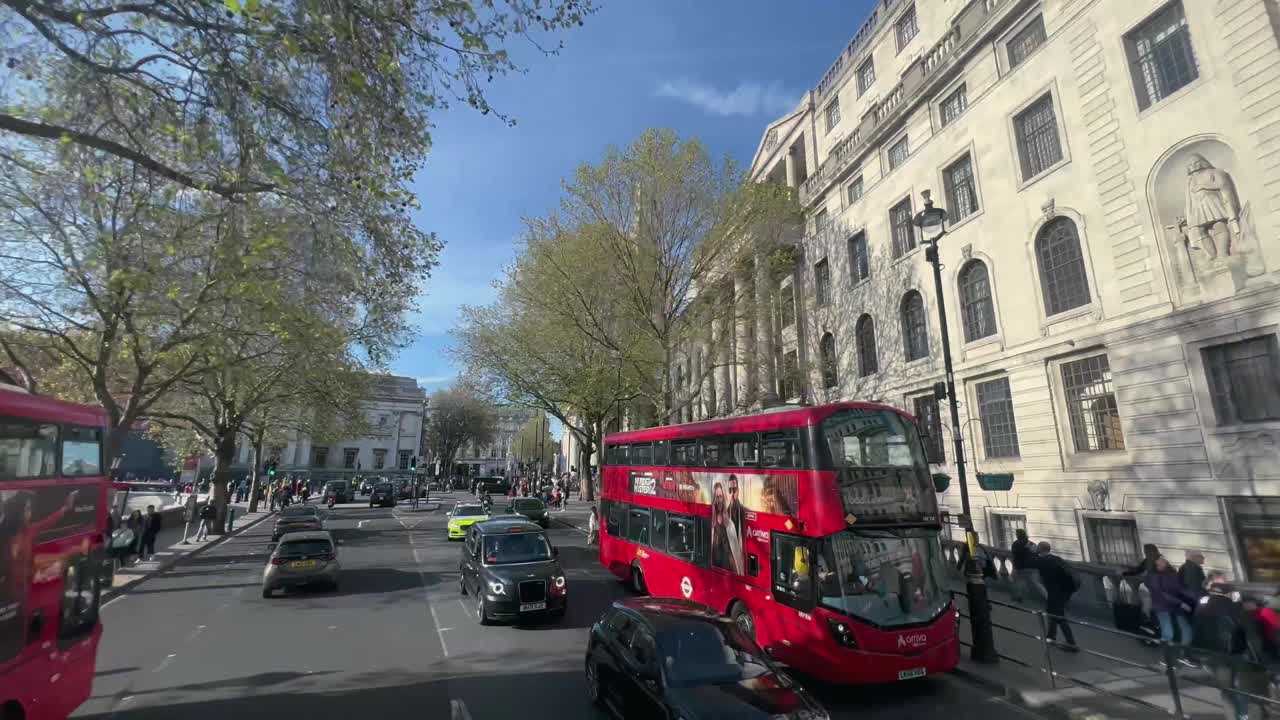 在夏日晴朗的日子里，蓝蓝的天空，背景是田野里的圣马丁教堂，特拉法加广场上挤满了传统的伦敦出租车和双层红色巴士视频素材