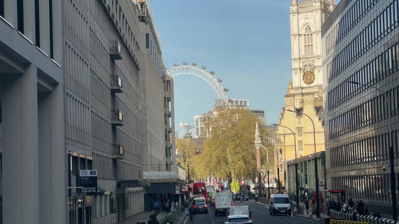 在晴朗的日子里，以著名的伦敦眼和威斯敏斯特教堂为背景的伦敦维多利亚街的交通视频素材