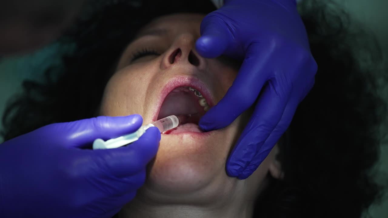 牙医用注射器给妇女的牙龈注射麻醉药视频下载