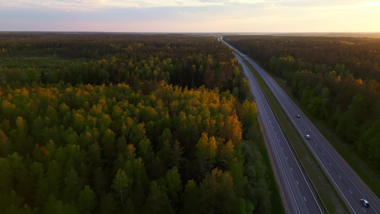 从空中俯瞰蜿蜒穿过茂密森林的高速公路，体验日落的美景视频素材