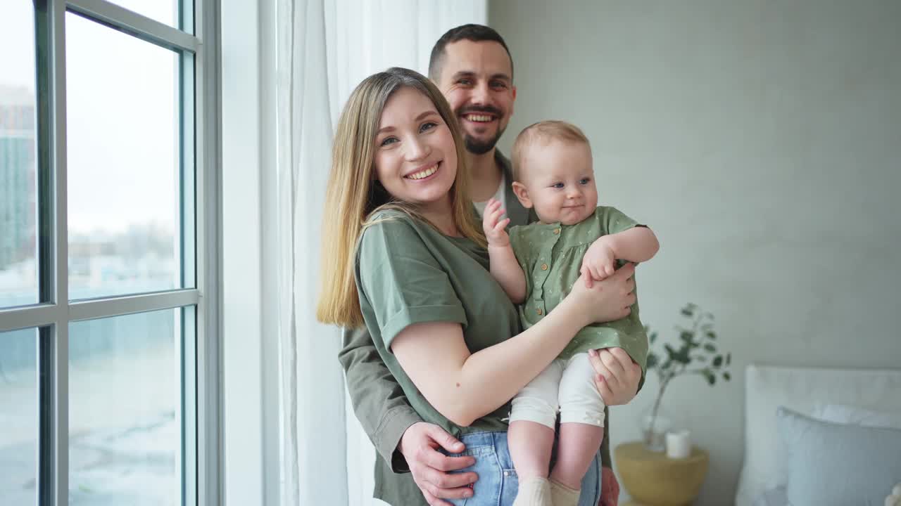 家庭美满。妈妈爸爸抱着蹒跚学步的孩子。妈妈，爸爸，宝贝，女孩，放松，一起玩，一起开心。女人，男人，抱着孩子，充满爱和关怀。母乳喂养婴儿的父母。视频素材