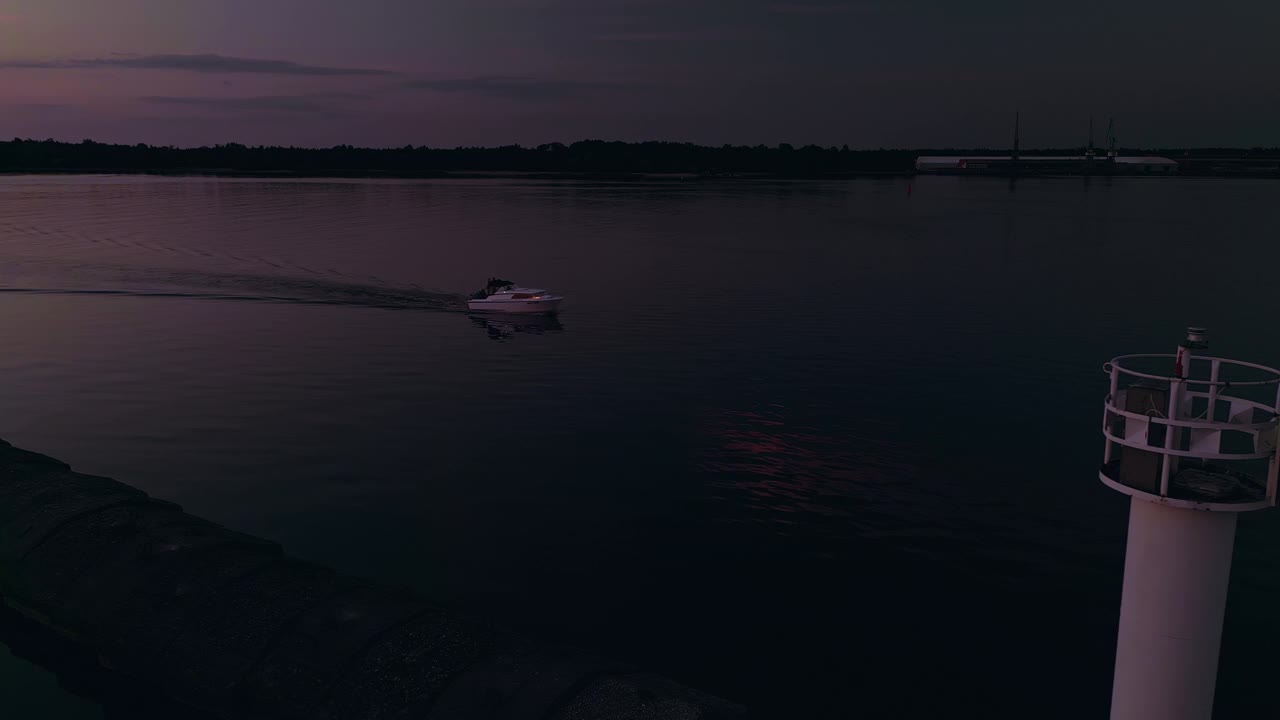 晚上看一艘船在灯塔旁航行，在平静的海面上营造一种宁静的气氛视频素材