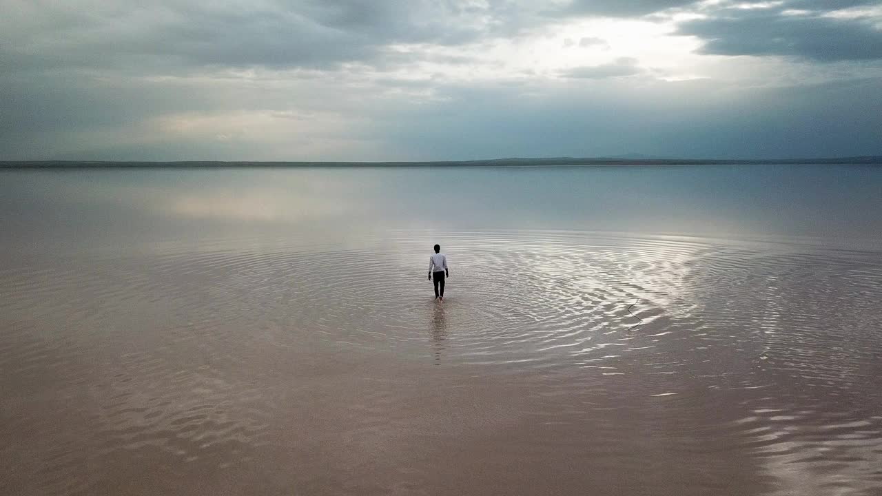 日落时分，一个人在热带海滩上跑步。一个人在海滩上奔跑的鸟瞰图视频下载