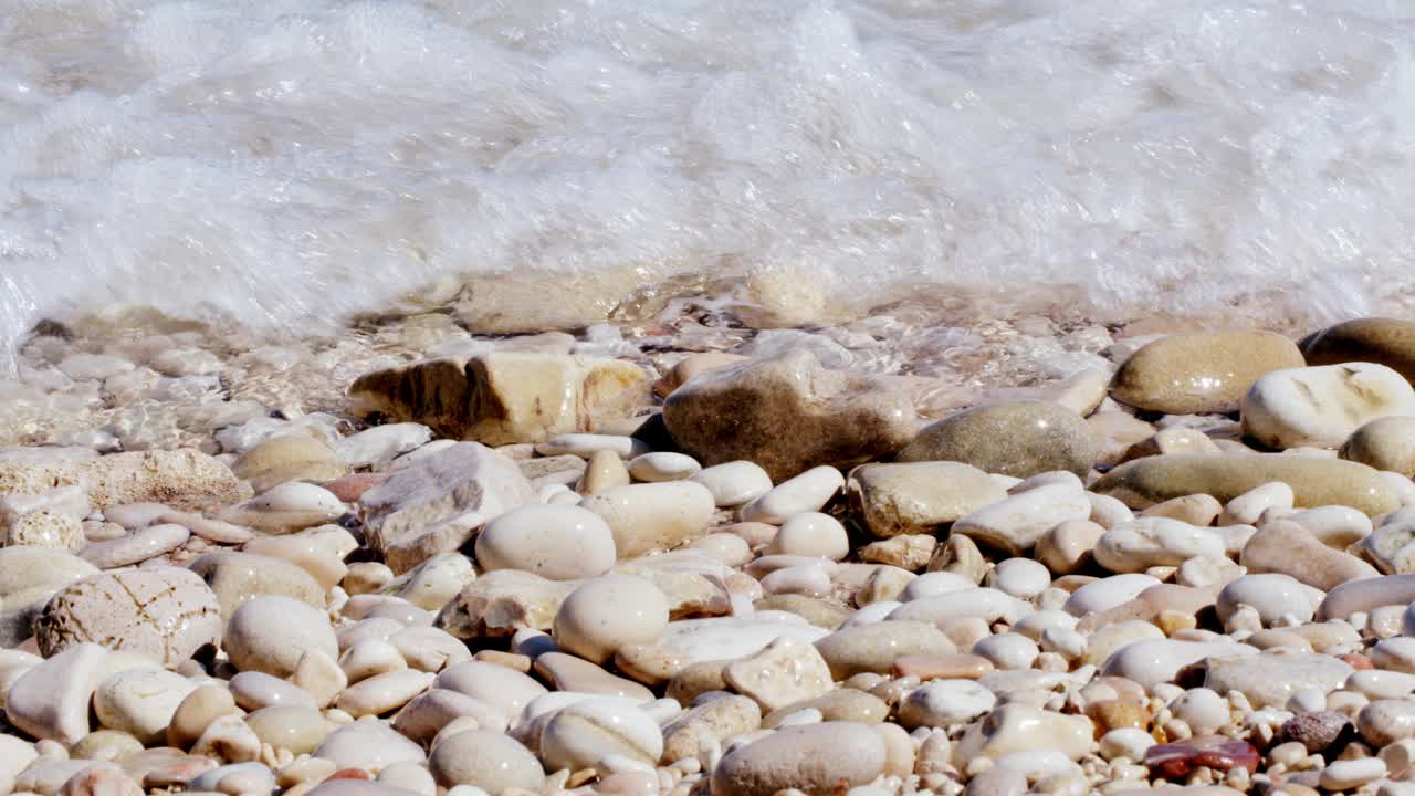 海水从海滩上的石头上流过视频下载