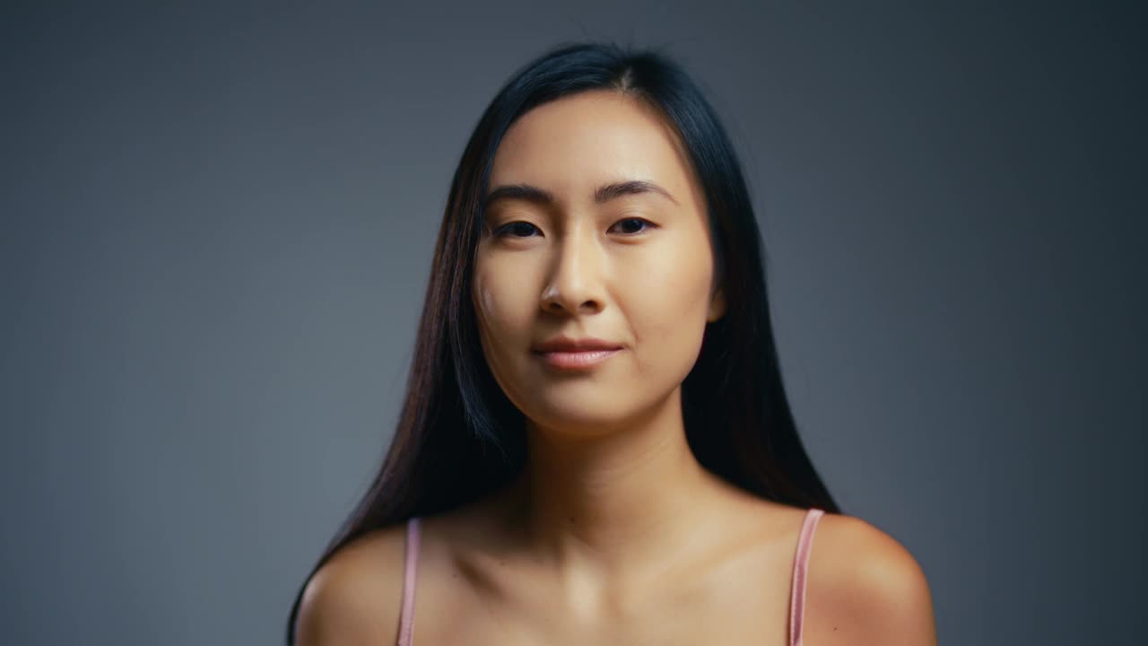 灰色背景上开朗的韩国女人微笑的肖像，青春和美丽视频下载