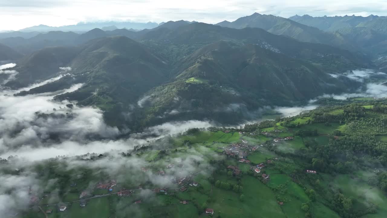 西班牙薄雾笼罩的山丘和山谷中的绿色村庄鸟瞰图。视频素材