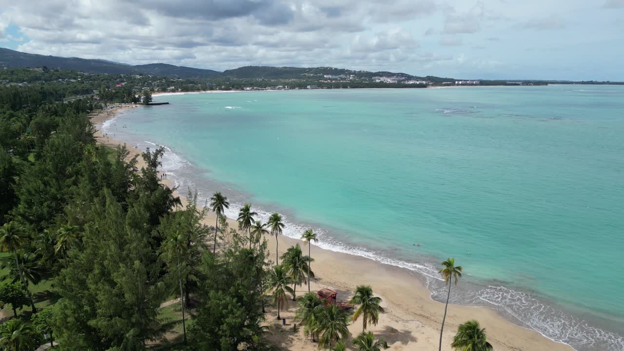 海浪冲击着波多黎各的沙滩(luquillo冲浪海岸海岸线)加勒比海旅游度假沙滩度假(棕榈树，山丘，亭子，空中无人机镜头)美丽的天堂风景视频素材