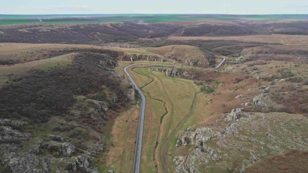 蜿蜒的道路穿过多布罗格峡谷，周围是岩石山丘，鸟瞰图视频素材