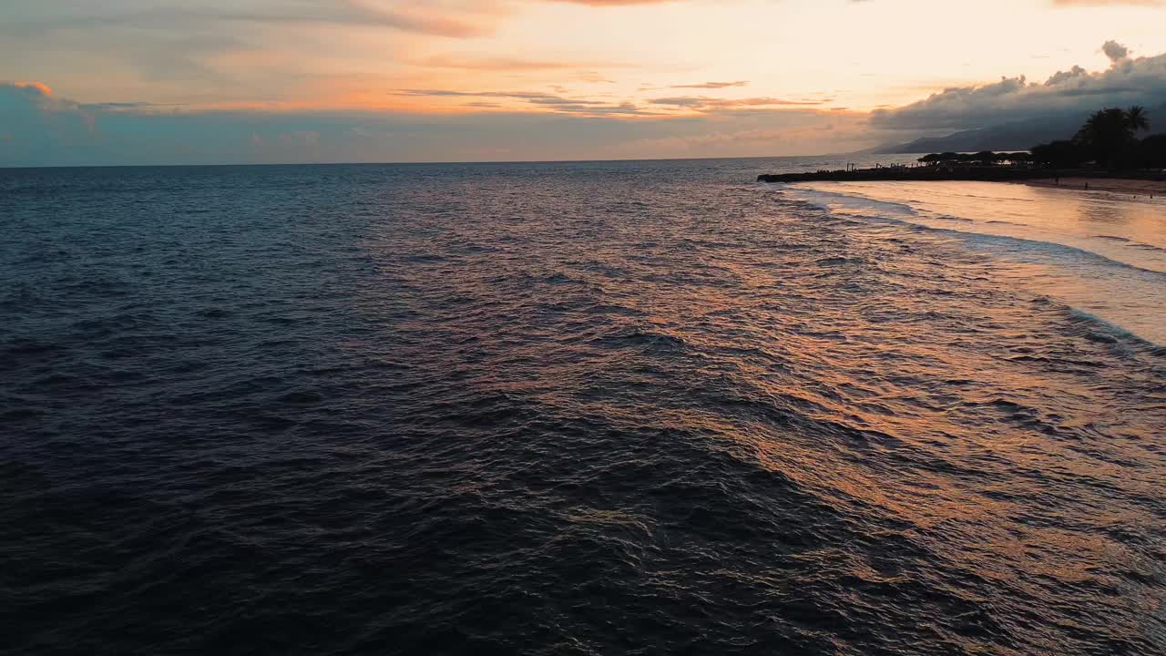 日落时海浪的鸟瞰图。夕阳越过海浪冲刷沙滩视频下载