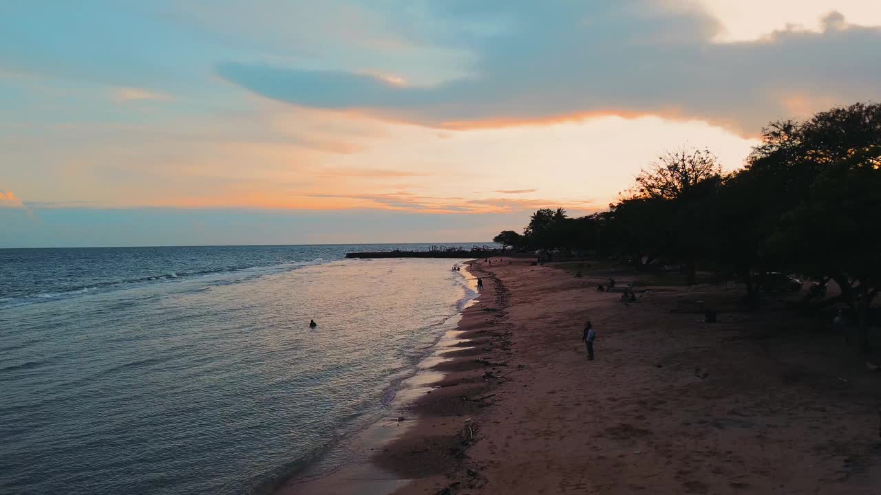 日落时海浪的鸟瞰图。夕阳越过海浪冲刷沙滩视频下载