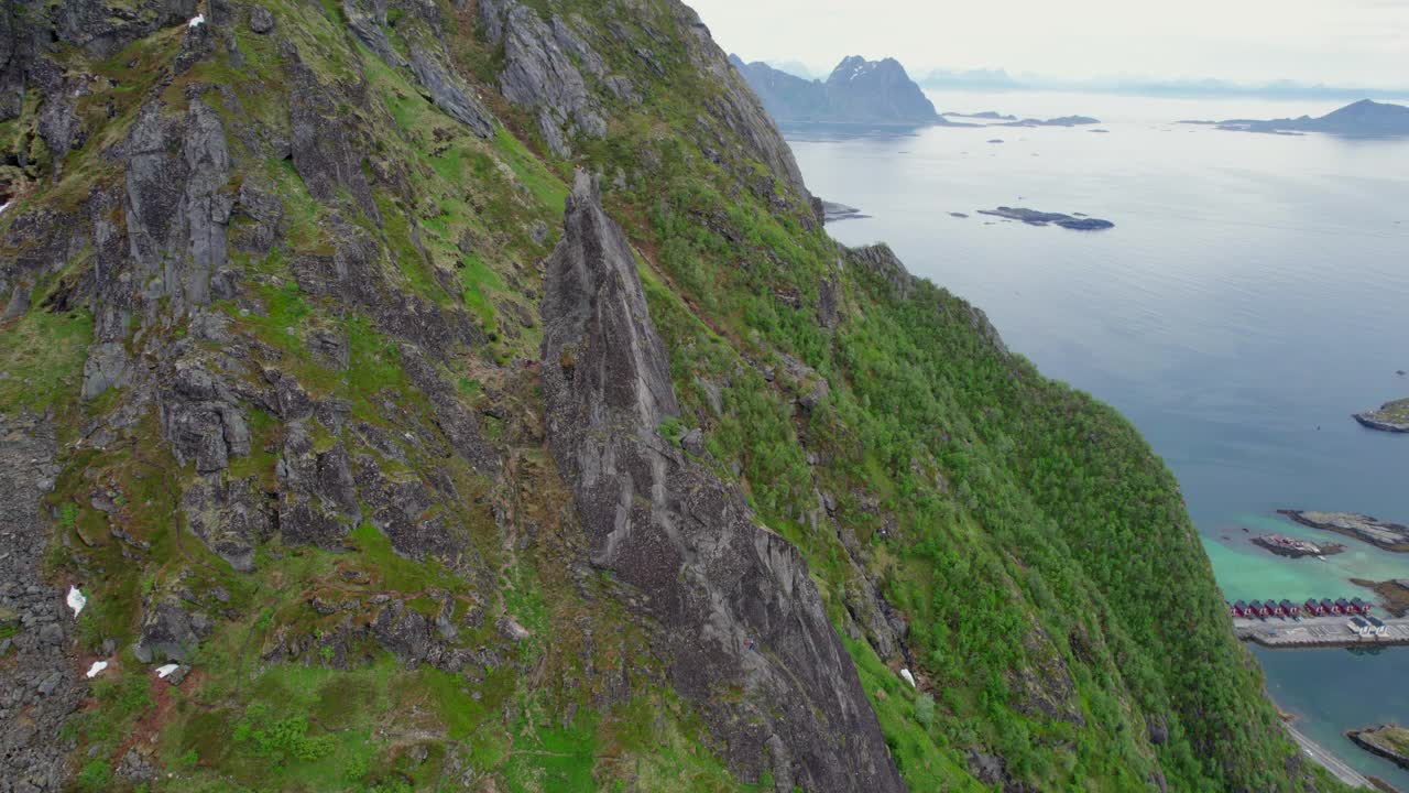 在轨道上鸟瞰Svolvaergeita(山羊)的岩石顶峰，在那里可以看到一个登山者在远处。在挪威的罗弗敦。视频素材