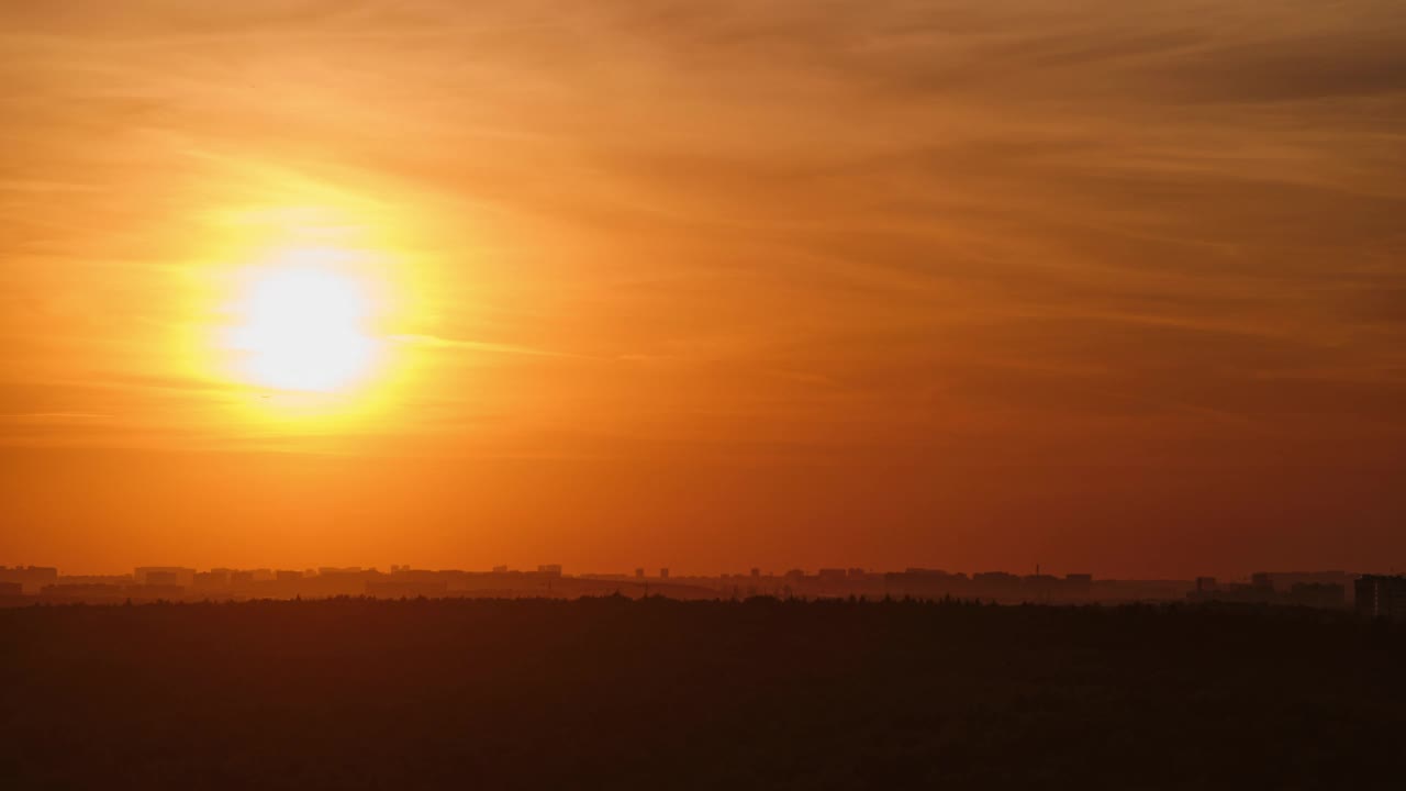 夕阳把红云沐浴在温暖的光线中，笼罩在傍晚城市高大的屋顶上，时光流逝视频下载