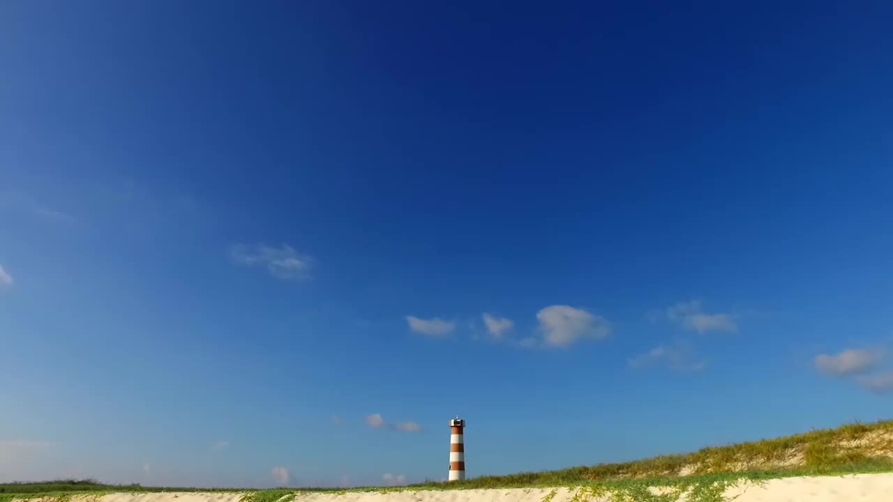 一座灯塔矗立在海洋中央的荒岛上，天空湛蓝，很少有云，沙滩雪白视频素材