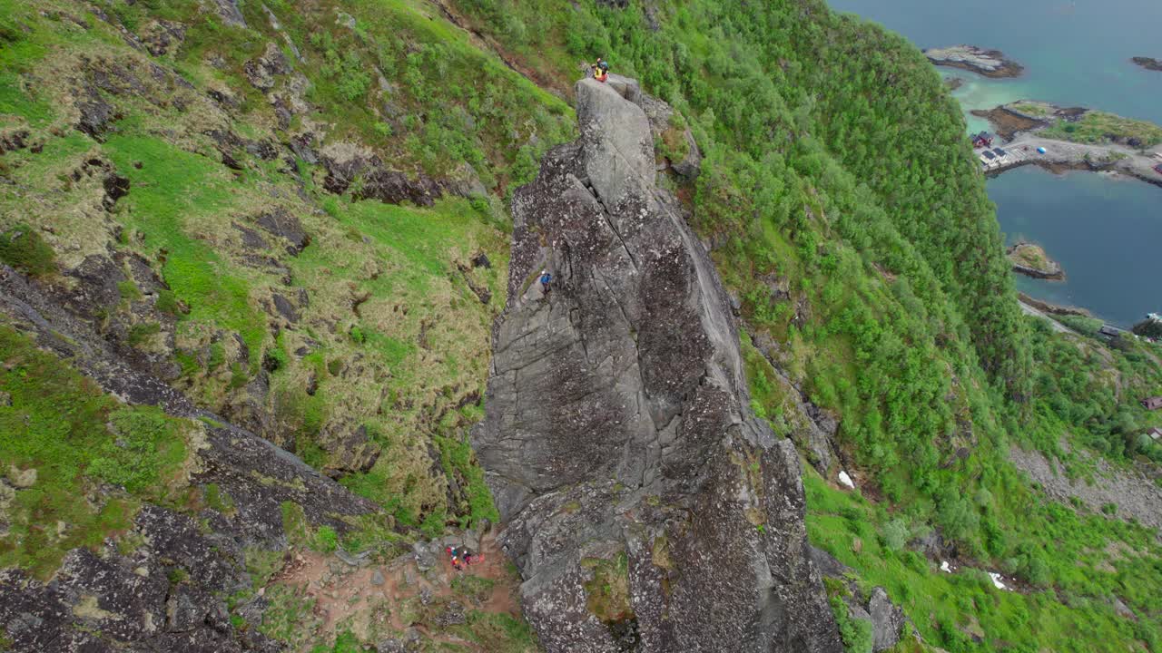 电影轨道鸟瞰图，一个登山者在春天的Svolvaergeita(山羊)的岩石顶峰的顶部。敦,挪威。视频素材