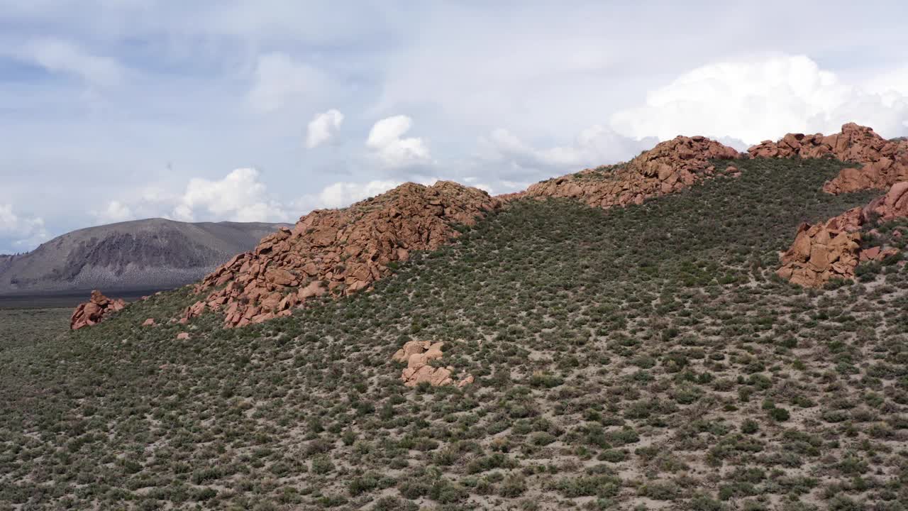 火山口山脊上有独特的红色岩层和稀疏的植被，映衬着风成山丘和天空的背景视频素材