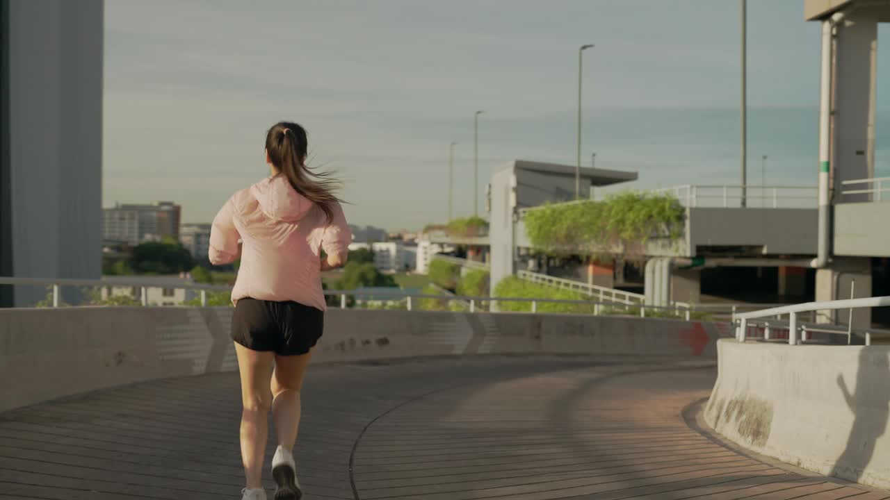 一位妇女在建筑物前的人行道上奔跑视频素材