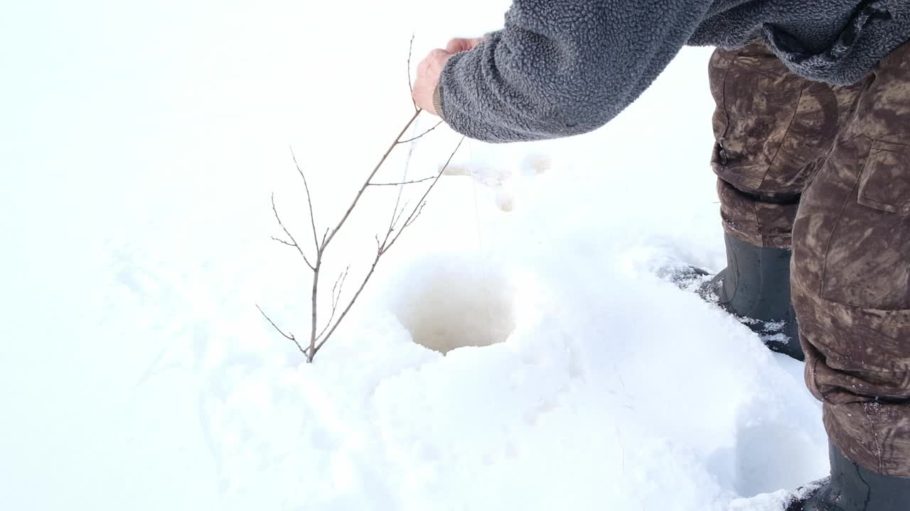 穿着冬季毛衣的人在结冰的湖面上准备钓鱼竿准备冰钓视频素材