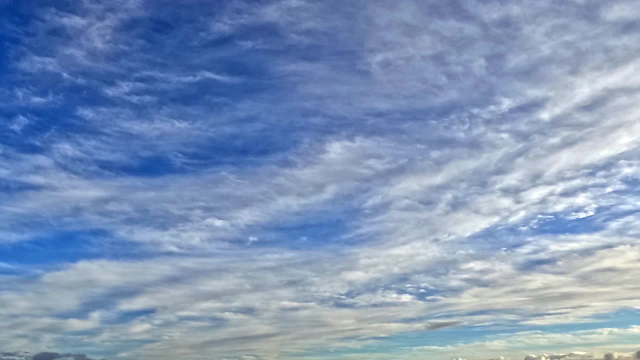 一望无际的蔚蓝天空点缀着蓬松的白云，一派宁静祥和的景象。朵朵白云飘过明亮的蓝色画布。视频素材