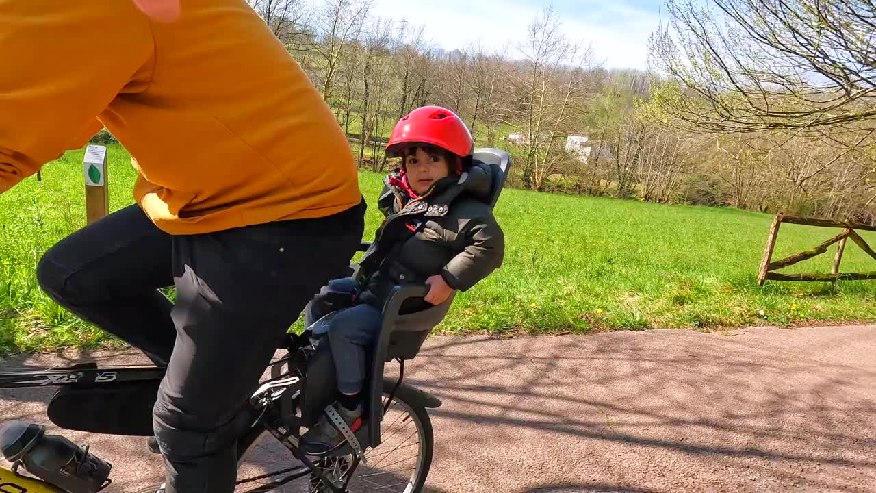 一个男人骑着自行车，孩子坐在儿童座椅上视频素材