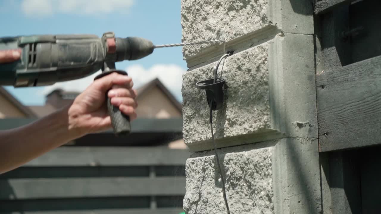 建筑工用锤子在墙上钻一个洞。冲击钻射孔器打孔特写视频下载