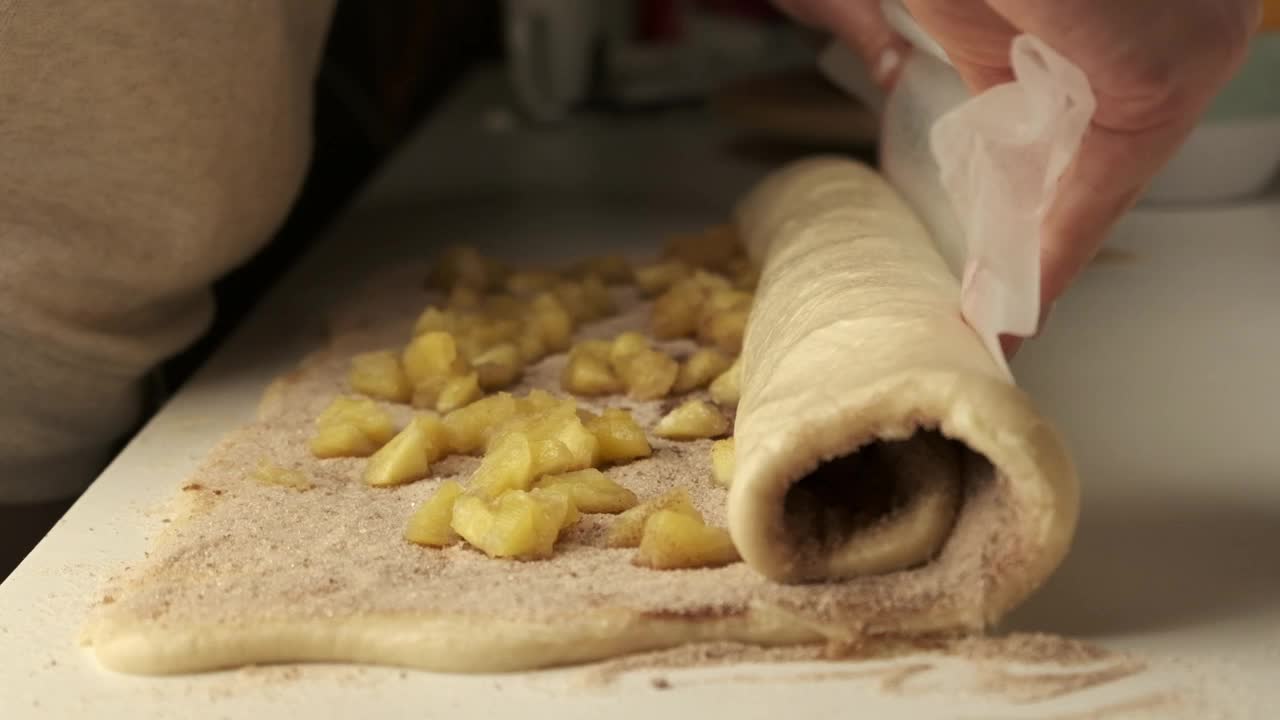 妇女用手把肉桂和糖包在擀好的面团里，做成肉桂包。制作肉桂包视频下载