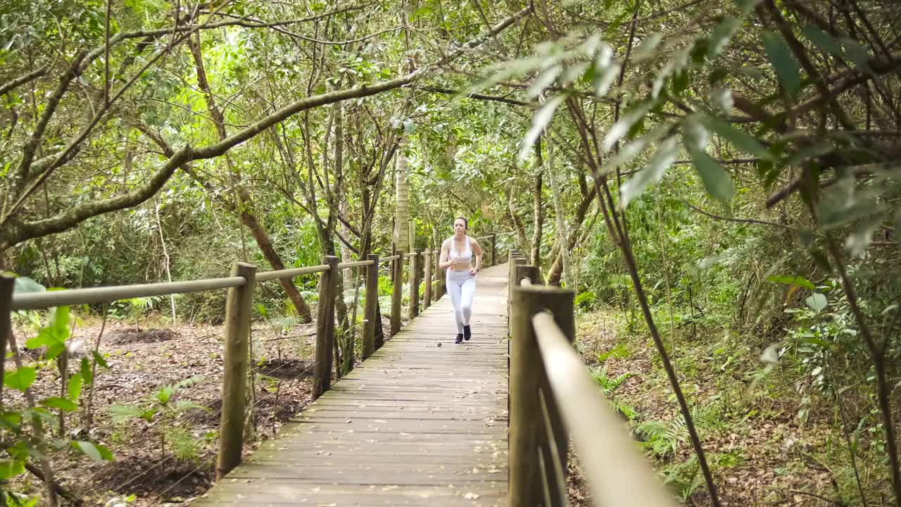 一个女人在森林中央的木小道上奔跑视频素材