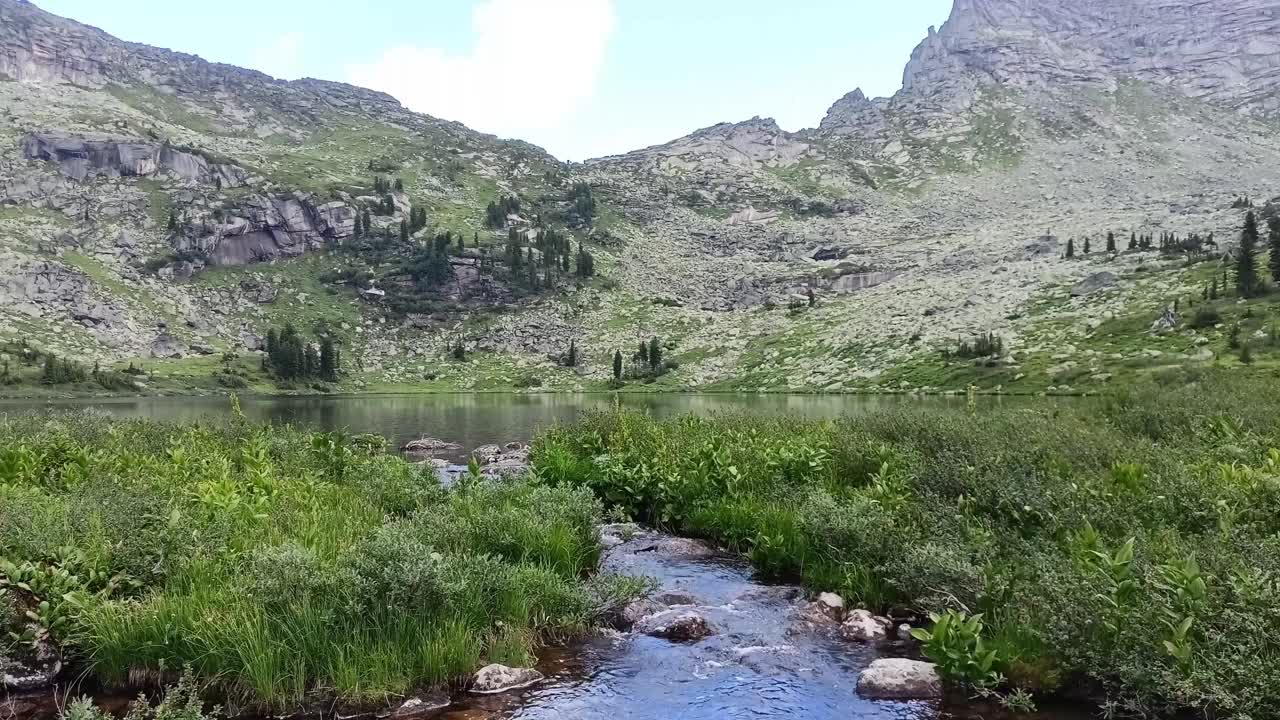 转弯处，转弯处:在一个阳光明媚的夏日，从一个大的山湖中流出的小溪的转弯处视频下载