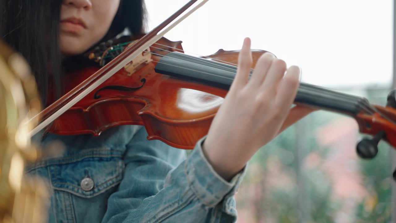 年轻的亚洲女子正在练习拉小提琴视频素材