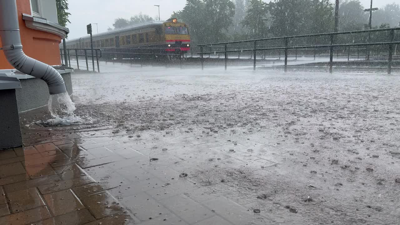 阴沟靠墙的建筑物和火车在后面，大雨后水流湍急视频素材