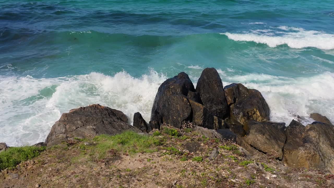 在西班牙科鲁尼亚的马尔皮卡海滩上，汹涌的海浪冲击着巨石。慢镜头视频素材