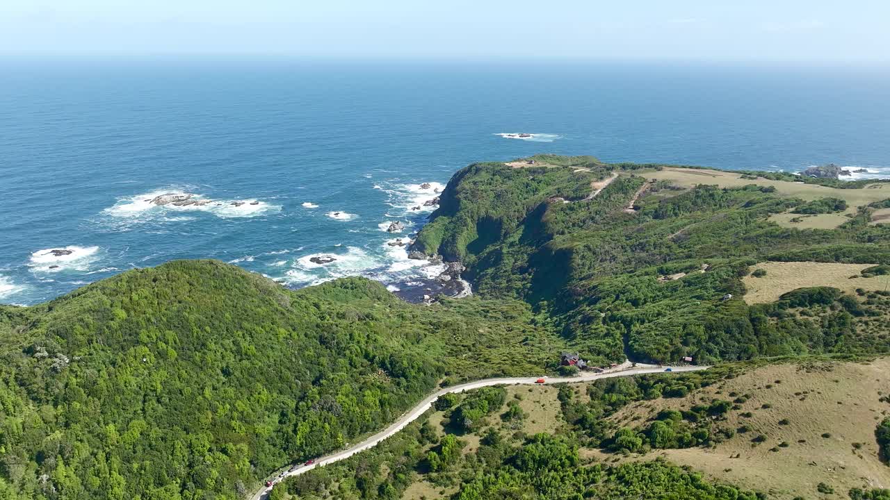 鸟瞰图，一条沿海公路蜿蜒穿过海边的绿色山坡，可以看到海洋的边缘。智鲁岛、智利视频素材