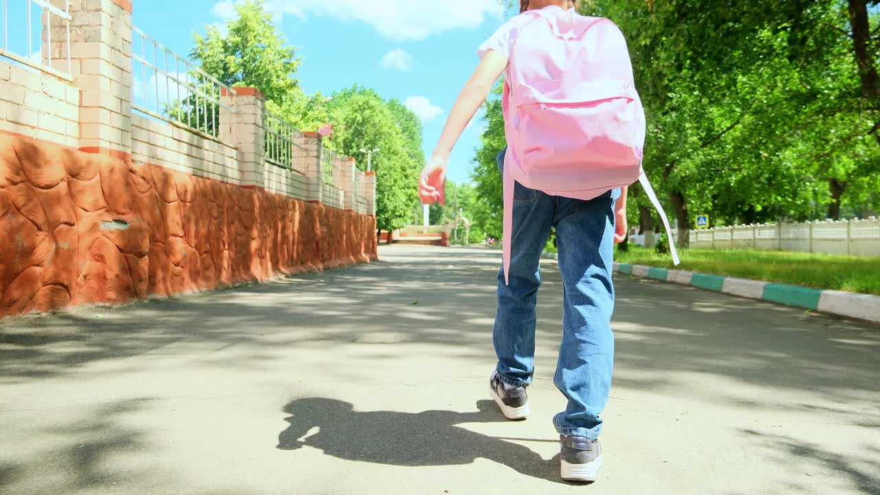 回到学校。一个背着背包的小女孩沿着马路穿过校园往学校跑。教育孩子的理念。一个背着背向背包的小孩跑向学校视频素材