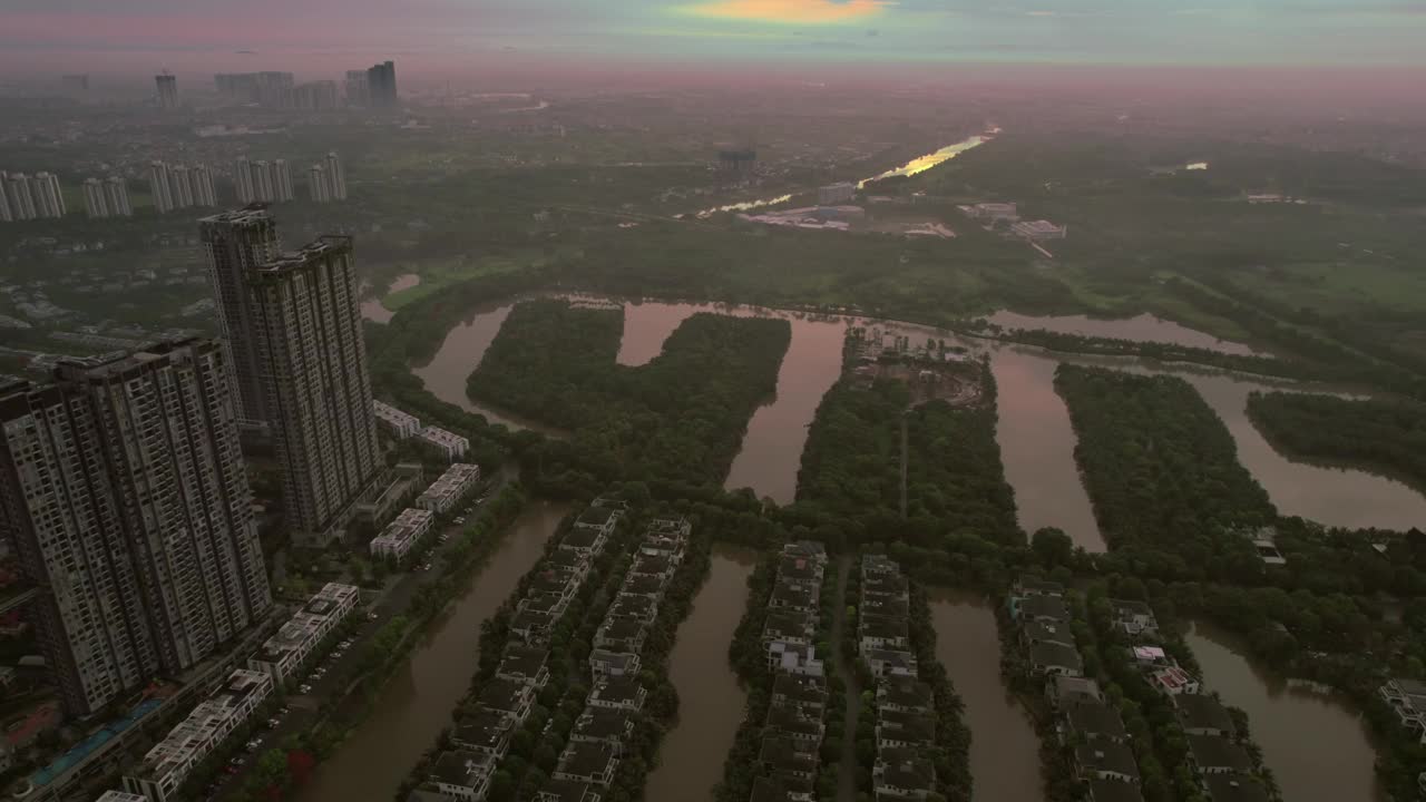 鸟瞰越南河内日落时的高层建筑、河流和被绿地包围的住宅区。视频素材