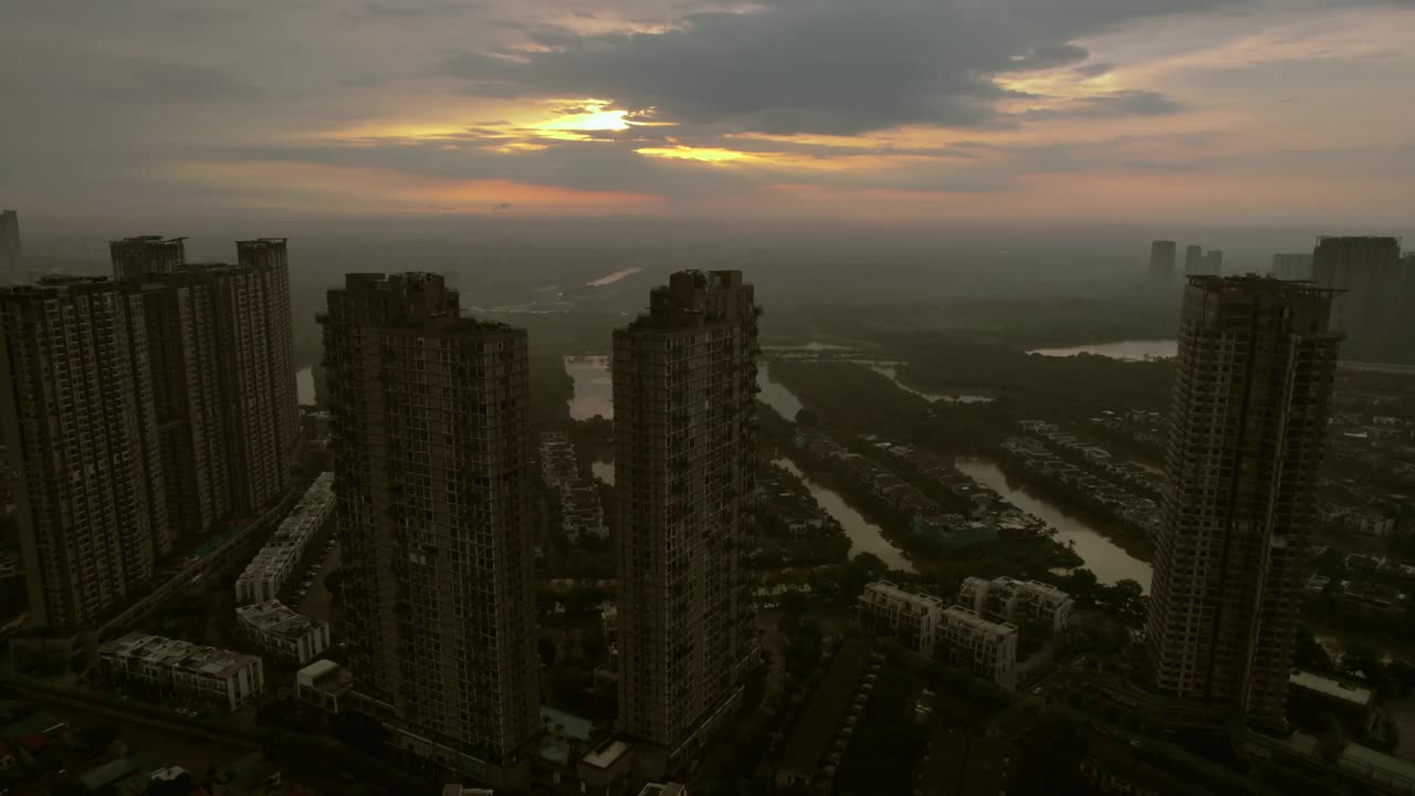 日落时分，河内的摩天大楼在河岸两旁的住宅区中拔地而起，展示了作为新城市发展象征的高层建筑。视频素材