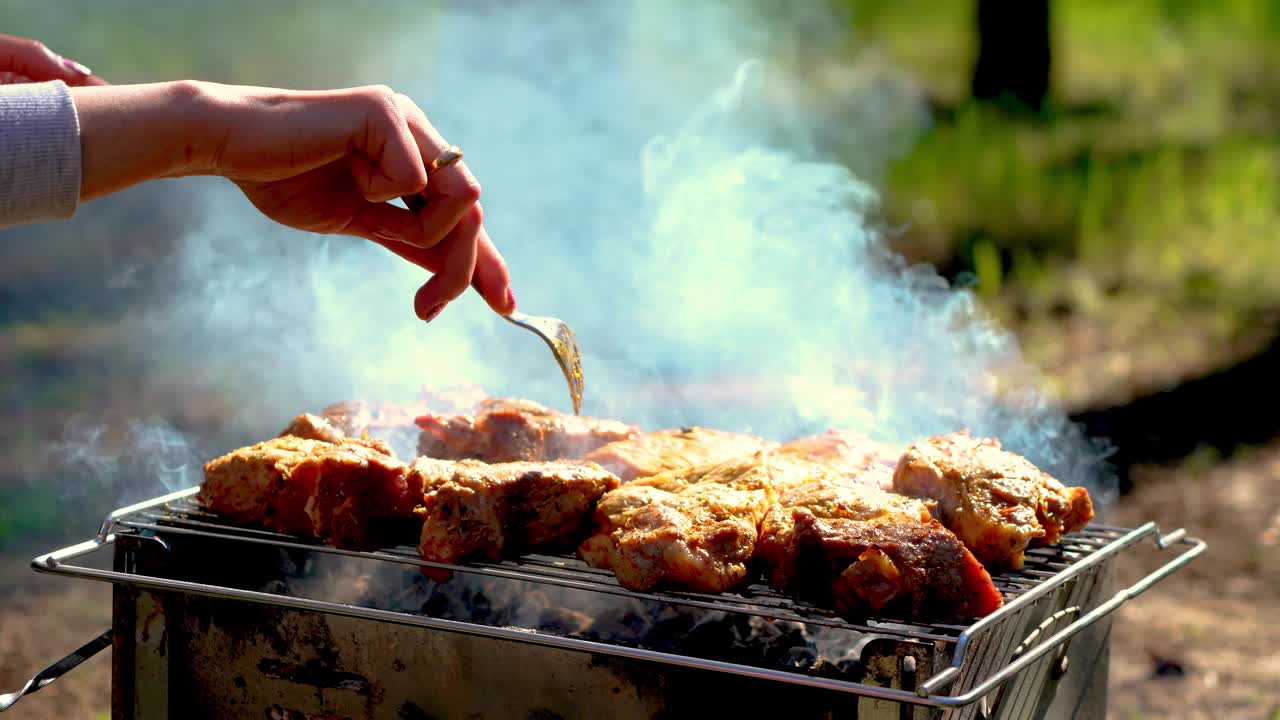 烹饪牛排的过程。外面烤架上烟熏的肉排。女人在烤肉架上煎多汁的牛排视频素材