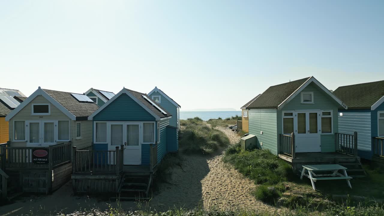 在多塞特郡的穆德福德，无人机飞过海滩小屋，飞向海滩和大海的4k视频视频下载