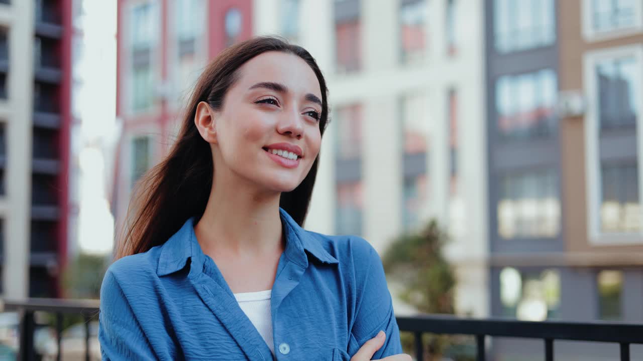 自信的年轻女子微笑着在公寓楼前摆姿势视频素材