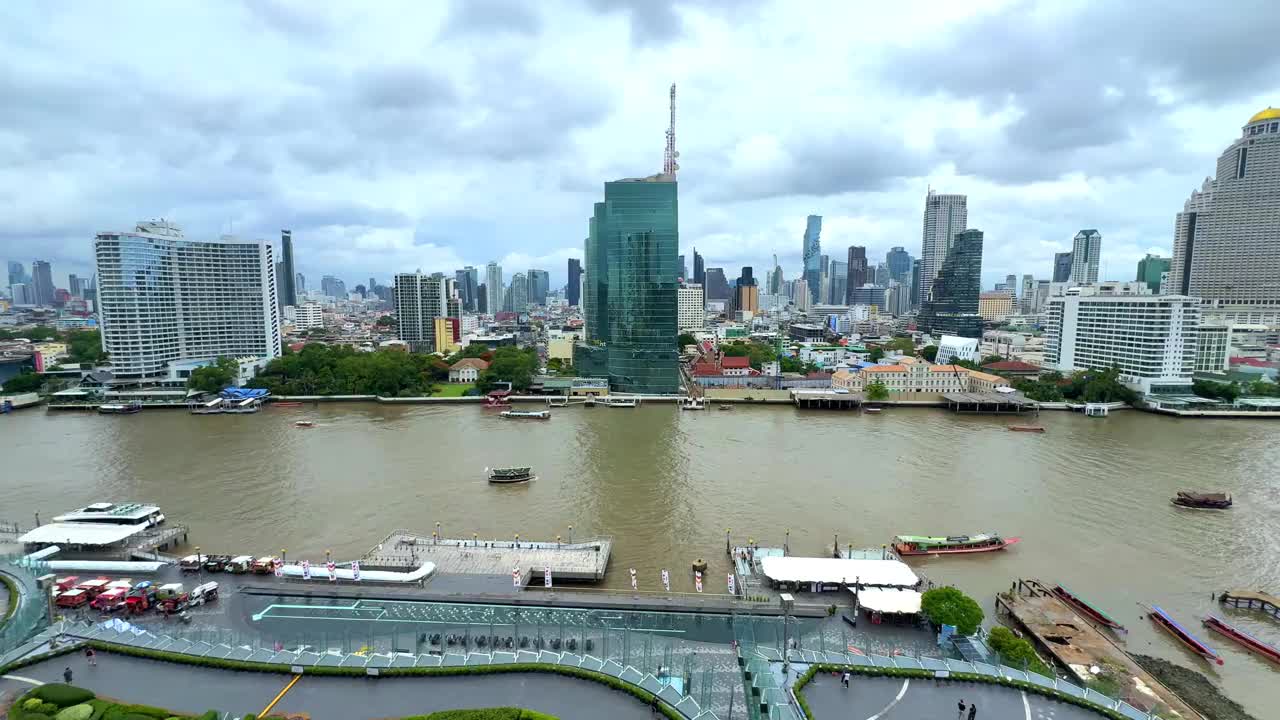 从IconSiam购物中心看曼谷的湄南河，船和渡轮在河上上下浮动，背景是曼谷的高层建筑视频素材