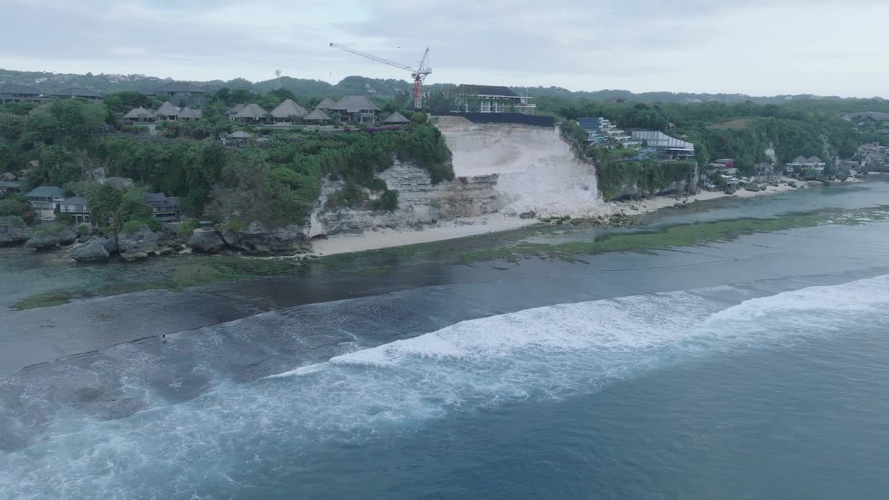 在印度尼西亚乌鲁瓦图岛巴厘岛的Bingin海滩，黄金时间日落与退潮礁石，过度开发的悬崖崩塌无人机视频素材