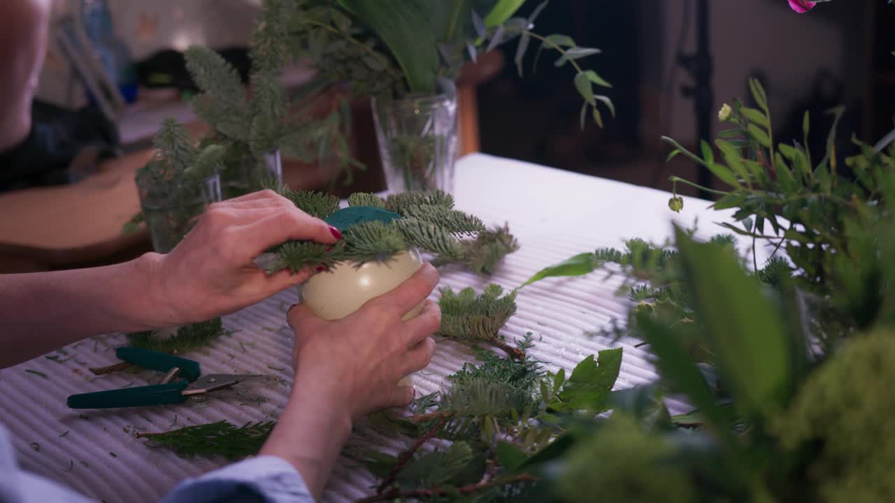 在花店做花束。用包装纸包装花束的特写。花商正在收集花束。视频素材