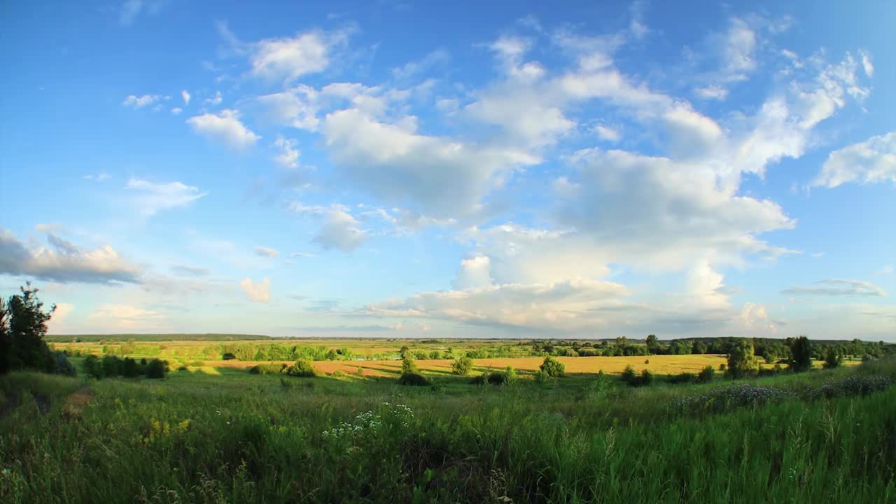 积云和雷雨云在有草地和树木的乡村河谷上空飞舞。风景如画的风景视频下载