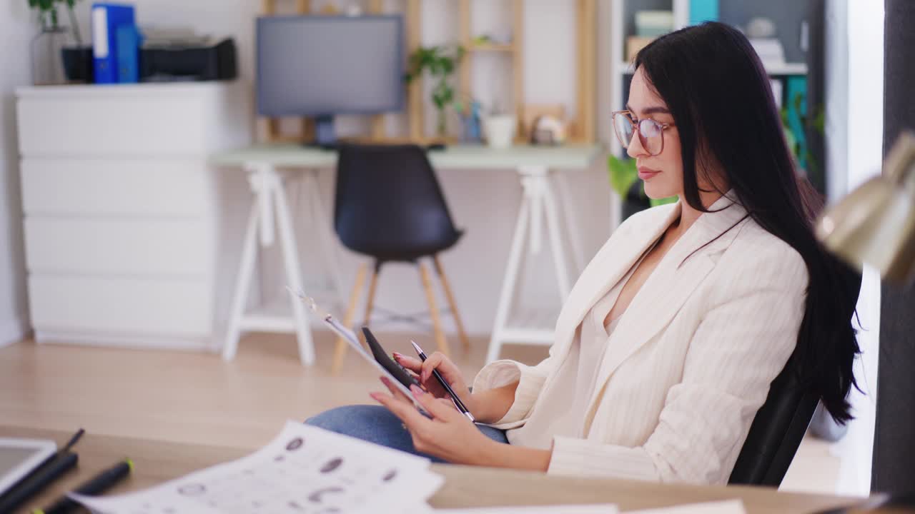 一个自信的女商人在办公室工作，用计算器计算，分析财务报告和公司状况视频素材