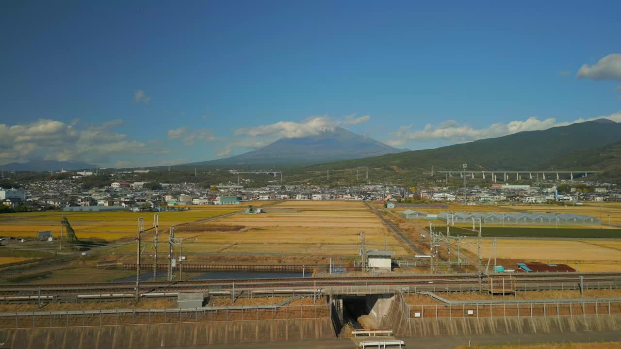 在日本静冈县，无人驾驶飞机飞过稻田，高速列车驶过视频下载